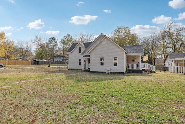 back of property with a lawn and fence