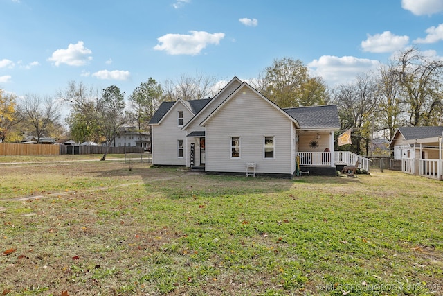 rear view of house with a yard, a wooden deck, and fence