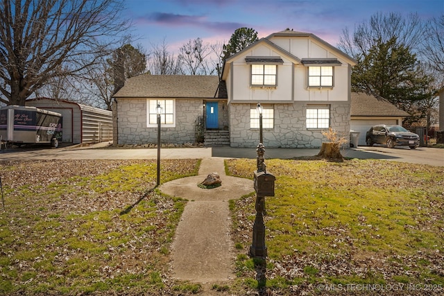 view of front of house with driveway, stone siding, a front lawn, and roof with shingles