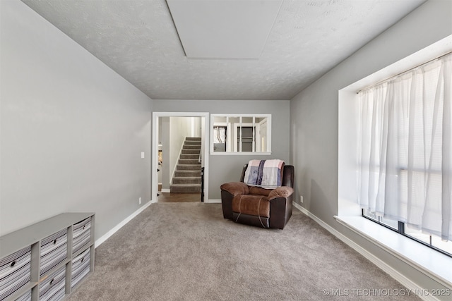 sitting room featuring carpet flooring, stairway, baseboards, and a textured ceiling