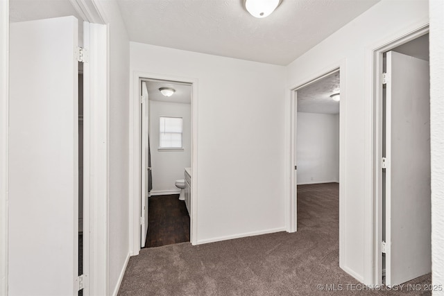 corridor featuring carpet floors, a textured ceiling, and baseboards