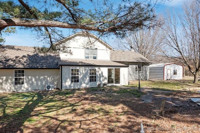 back of property featuring a shingled roof, a yard, an outdoor structure, and a storage shed