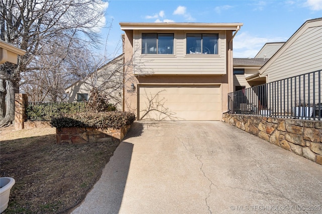 view of front facade with concrete driveway, fence, and an attached garage