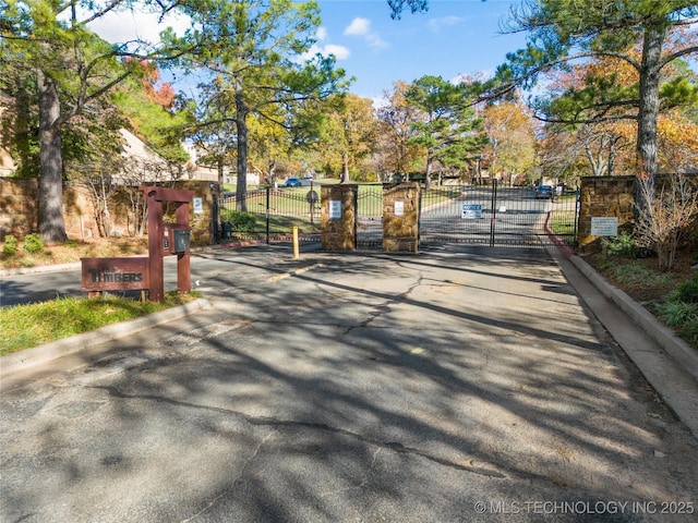 view of road with curbs, a gated entry, and a gate