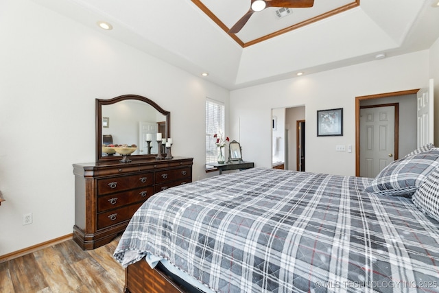 bedroom with a ceiling fan, baseboards, visible vents, light wood-style floors, and a tray ceiling