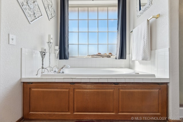 bathroom with a healthy amount of sunlight, a bathing tub, and a textured wall