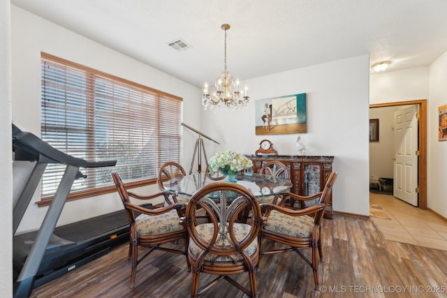 dining area featuring baseboards, wood finished floors, visible vents, and an inviting chandelier