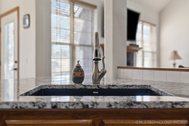 interior details with a sink and light stone countertops