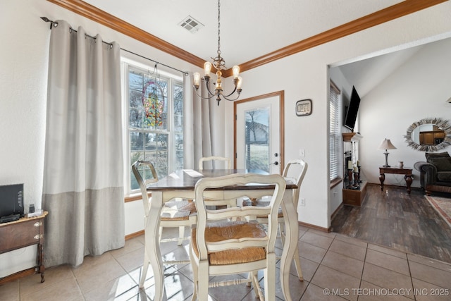 dining room featuring crown molding, light tile patterned floors, lofted ceiling, visible vents, and an inviting chandelier