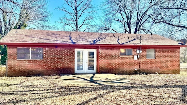 back of property with a shingled roof, french doors, and brick siding