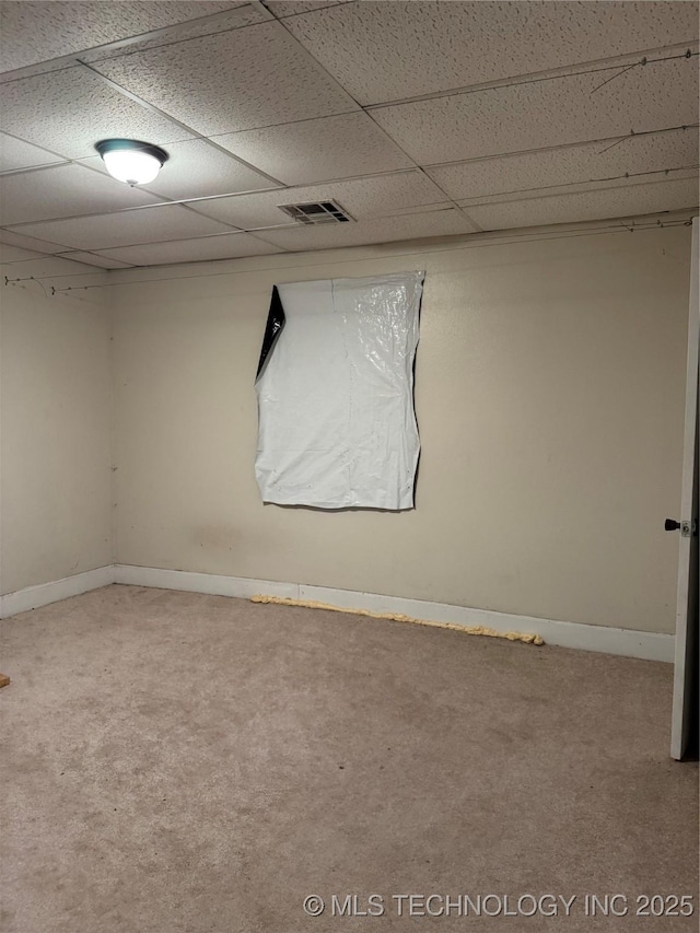 carpeted empty room with a paneled ceiling, baseboards, and visible vents