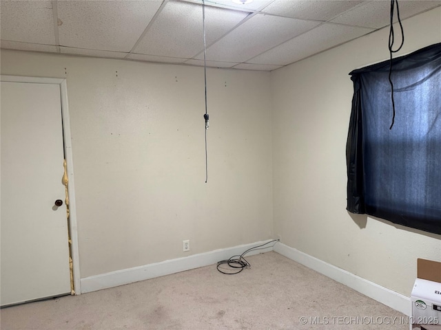 carpeted empty room featuring a paneled ceiling and baseboards