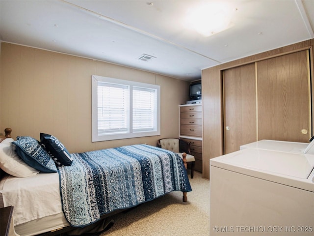 bedroom featuring light carpet, a closet, washing machine and clothes dryer, and visible vents