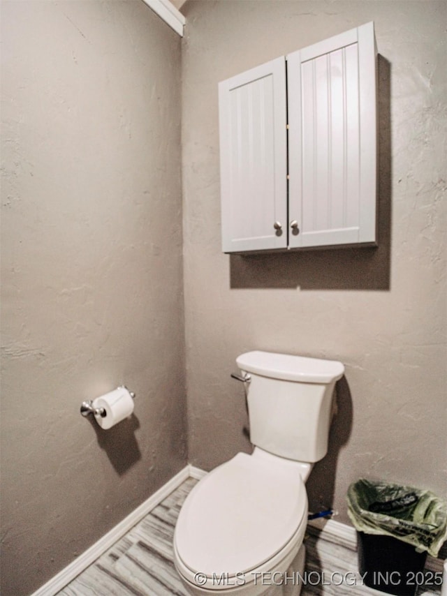 bathroom with wood finished floors, toilet, and baseboards