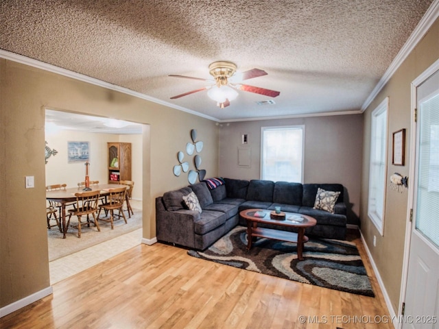 living area with a textured ceiling, ceiling fan, wood finished floors, baseboards, and ornamental molding