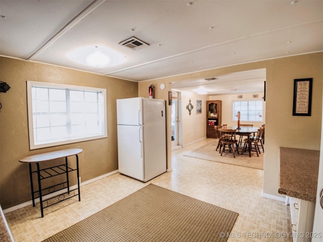 kitchen featuring baseboards, visible vents, dark countertops, freestanding refrigerator, and light floors