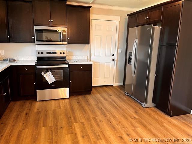 kitchen with dark brown cabinets, stainless steel appliances, and light countertops