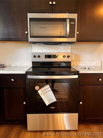 kitchen with appliances with stainless steel finishes, light countertops, light wood-style flooring, and dark brown cabinets