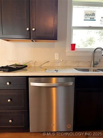 kitchen with light stone countertops, a sink, stainless steel dishwasher, and dark brown cabinets