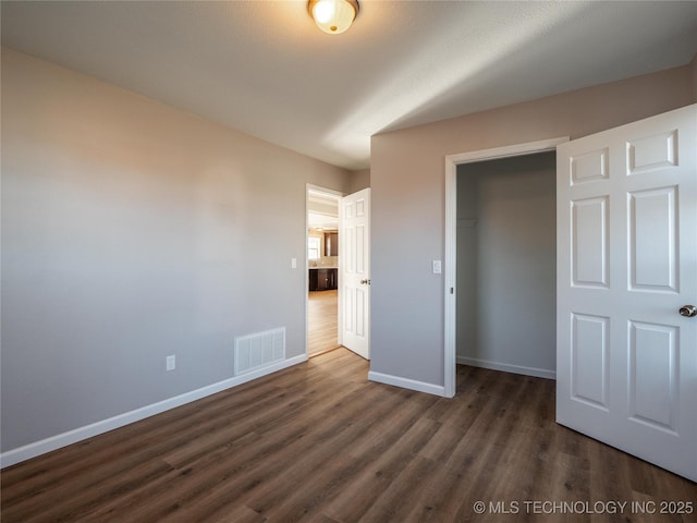 unfurnished bedroom featuring a closet, dark wood-style flooring, visible vents, and baseboards