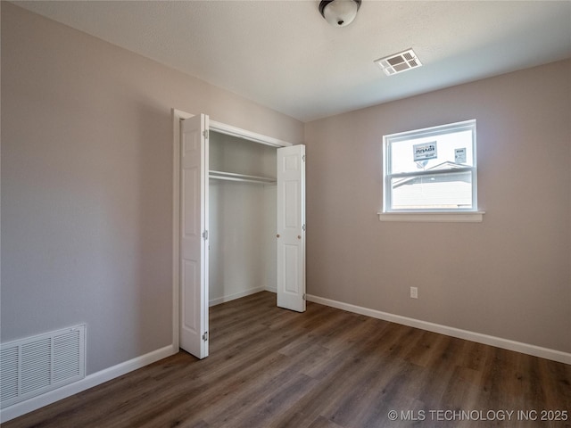 unfurnished bedroom with visible vents, dark wood finished floors, and baseboards