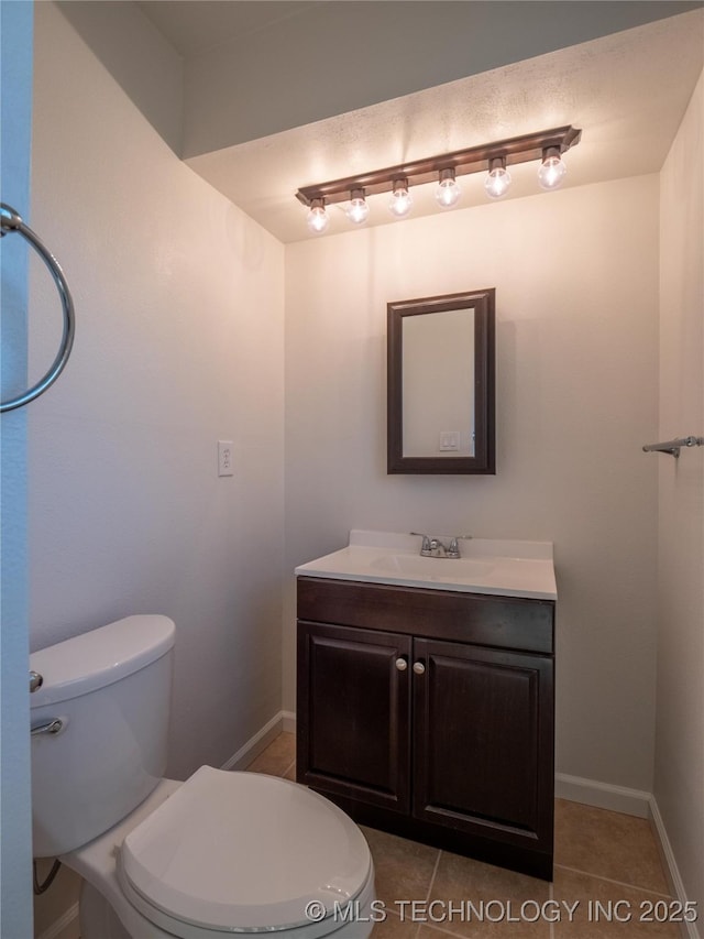 bathroom featuring tile patterned flooring, baseboards, vanity, and toilet