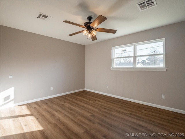 unfurnished room with baseboards, visible vents, and dark wood-style flooring