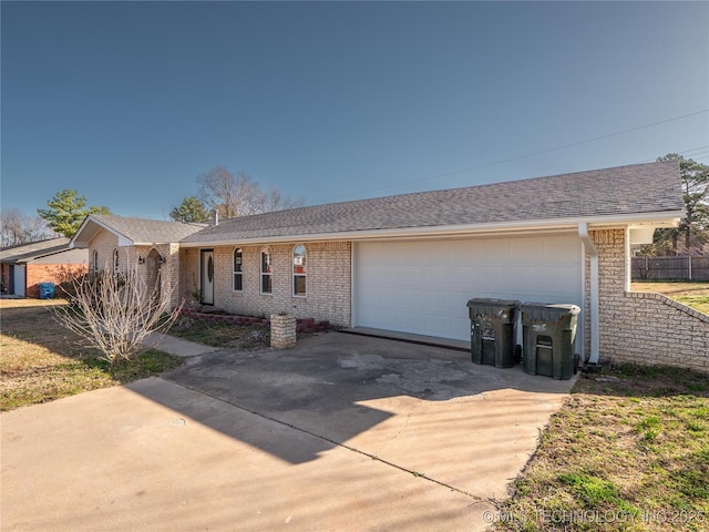 ranch-style house featuring a garage, concrete driveway, brick siding, and roof with shingles