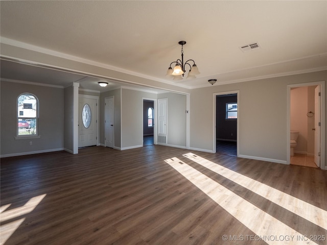 unfurnished living room featuring visible vents, dark wood-type flooring, ornamental molding, a chandelier, and baseboards