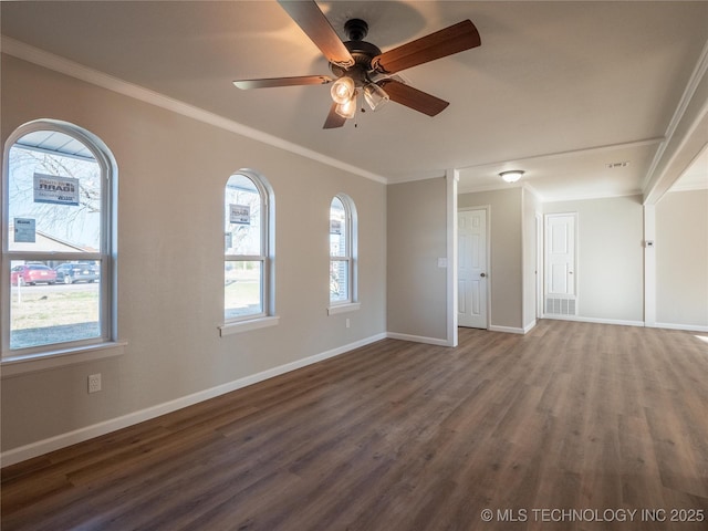 empty room featuring dark wood-type flooring, crown molding, baseboards, and a ceiling fan