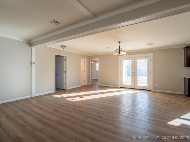 unfurnished living room with crown molding, an inviting chandelier, wood finished floors, and baseboards