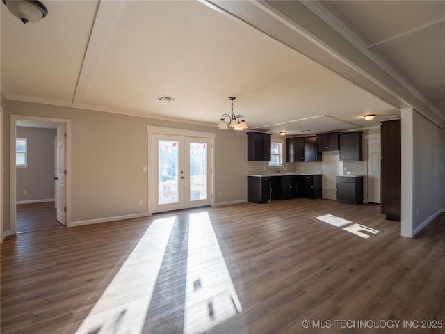 unfurnished living room featuring dark wood-type flooring, visible vents, baseboards, ornamental molding, and french doors