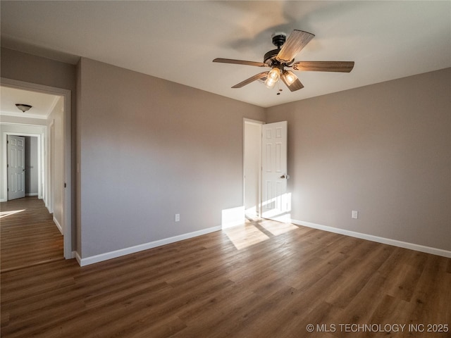 unfurnished room featuring a ceiling fan, dark wood finished floors, and baseboards