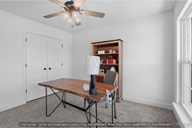 home office with light carpet, a ceiling fan, and baseboards