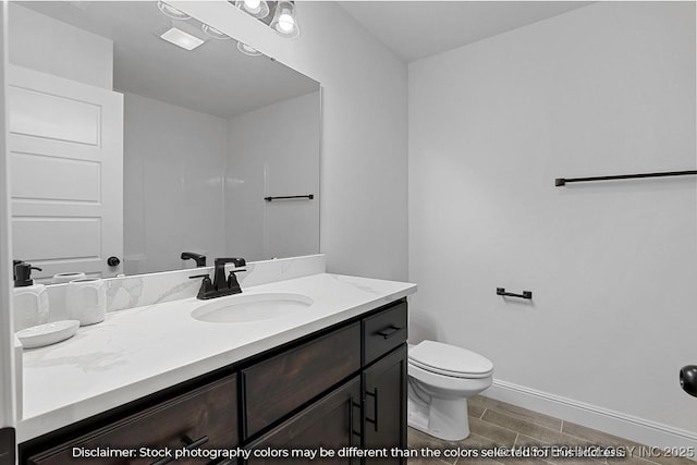 bathroom with wood tiled floor, baseboards, vanity, and toilet