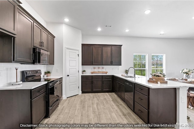 kitchen with a sink, black appliances, dark brown cabinets, and light countertops