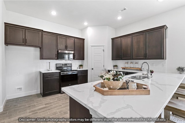 kitchen featuring a breakfast bar area, a peninsula, a sink, stainless steel appliances, and backsplash