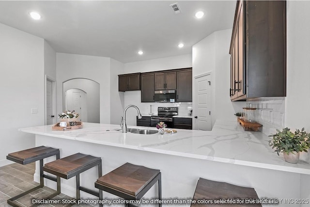 kitchen featuring visible vents, decorative backsplash, appliances with stainless steel finishes, a sink, and a peninsula