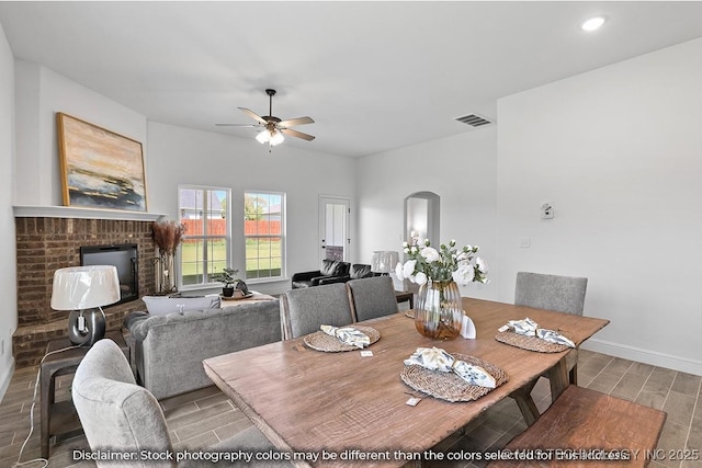 dining area with arched walkways, a fireplace, visible vents, baseboards, and light wood-type flooring