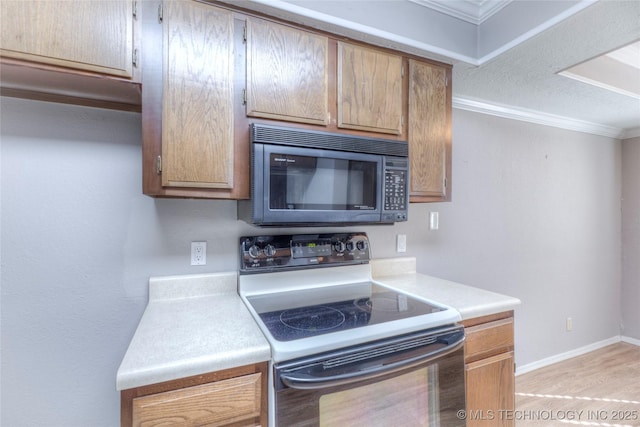 kitchen with brown cabinets, crown molding, range with electric stovetop, light countertops, and black microwave