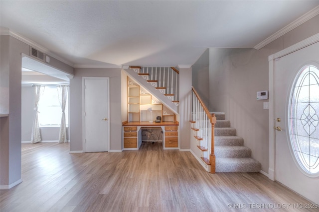 entrance foyer with ornamental molding, light wood finished floors, stairway, and visible vents