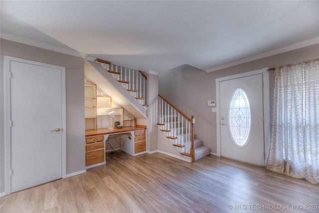 foyer with baseboards, stairway, light wood finished floors, built in desk, and crown molding