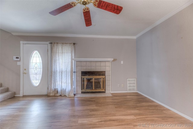 unfurnished living room with light wood finished floors, stairway, ornamental molding, a textured ceiling, and a tile fireplace