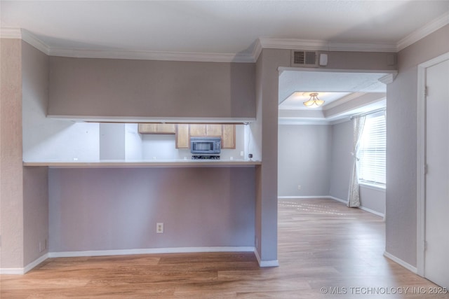 kitchen with baseboards, visible vents, light wood-style flooring, light countertops, and crown molding