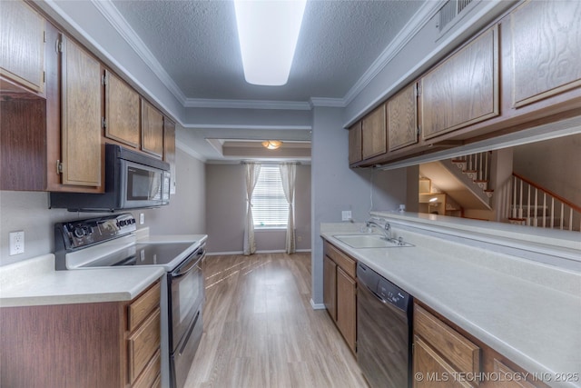 kitchen with brown cabinets, light countertops, ornamental molding, a sink, and black appliances