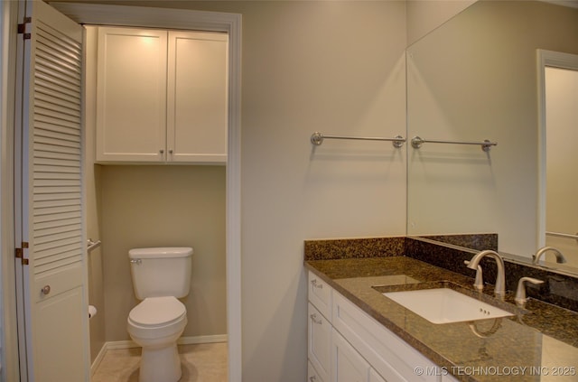 bathroom with toilet, vanity, baseboards, a closet, and tile patterned floors