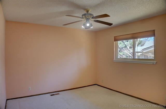 carpeted spare room featuring a ceiling fan, baseboards, visible vents, and a textured ceiling