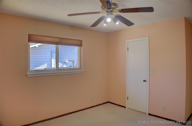 empty room featuring light carpet, a textured ceiling, and baseboards