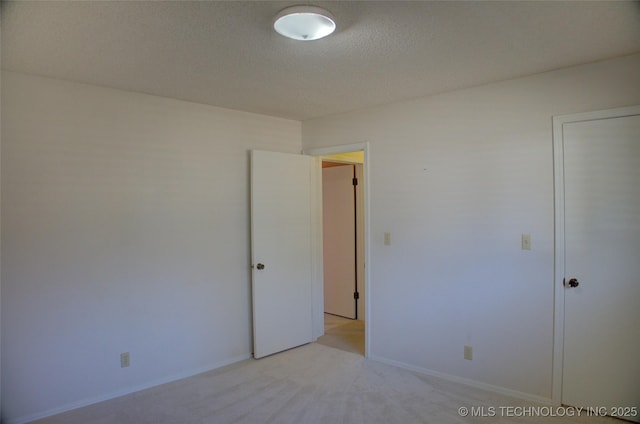 empty room with a textured ceiling and light carpet