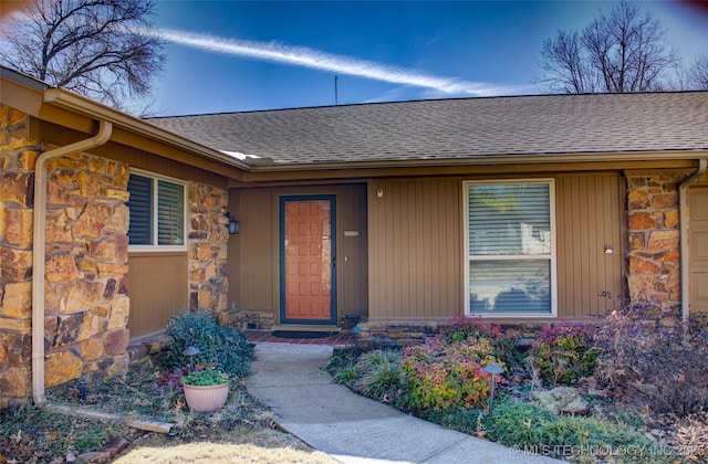 property entrance with a shingled roof and stone siding